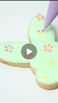 a cookie decorated like a butterfly being cut by a person with a purple toothbrush