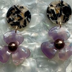 Our three-petal pearl water poppy drop earring is a must-have for any stylish babe. This lightweight, sweet pair features a light purple acrylic flower with a deep brown pearl-studded center, and a contrasting beige and black hand-swirled acrylic stud.   Designed for Closet Rehab. Handmade in Pittsburgh, PA. Made in the USA. Materials: acrylic, brass base posts/jump rings with 18k gold plating Hypoallergenic  Our accessories are handcrafted from colorful acrylic. To preserve your Closet Rehab products, we recommend storing safely in our pouches. Avoid contact with harsh substances like perfumes and hairsprays. Items with plated metals naturally tarnish over time when exposed to body oils and other natural elements. Please handle with care, as excessive dropping, wear and tear, and improper Trendy Purple Flower Earrings For Gift, Trendy Purple Flower Jewelry, Purple Acrylic, September Birthstone Jewelry, Acrylic Flower, August Birthstone Jewelry, July Birthstone Jewelry, Mini Hoop Earrings, Beige And Black