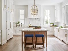 two blue stools sit at the center of a kitchen island in front of white cabinets