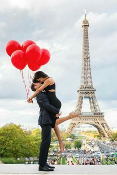 a man and woman kissing in front of the eiffel tower with red balloons