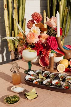 an arrangement of sushi and other food on a table next to some cacti