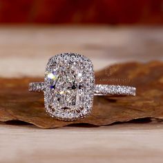 a diamond ring sitting on top of a leaf covered ground next to a wooden surface