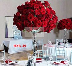 a vase filled with red roses sitting on top of a table next to other tables