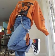 a person wearing an orange shirt and jeans with chains attached to their ankles