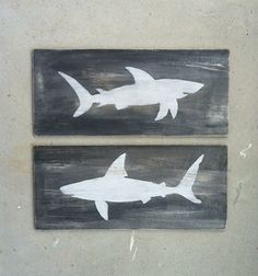 two wooden signs with white sharks painted on them, one is black and the other is gray