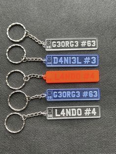 four keychains with name tags on them sitting next to each other in front of a gray background