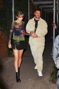 a man and woman walking down a sidewalk at night