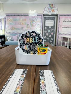 a wooden table topped with a white container filled with candy