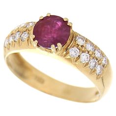 a yellow gold ring with an oval shaped ruby stone surrounded by small white diamond accents