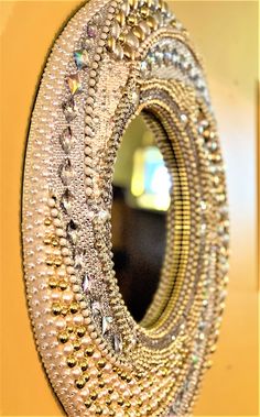 a decorative mirror hanging on the wall next to a yellow door with beads and chains around it