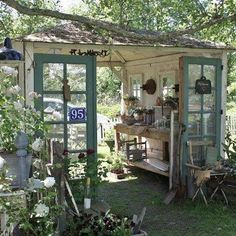 a small shed with lots of potted plants on the front and back porch area