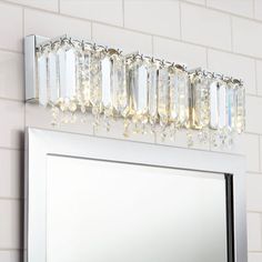 a bathroom vanity with a mirror and lights on the wall next to it is white tiled walls