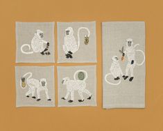 four embroidered napkins with monkeys on them and one monkey holding a pineapple in its mouth