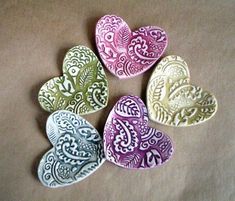 five hearts are sitting on a table with white and purple designs in the shape of paisleys