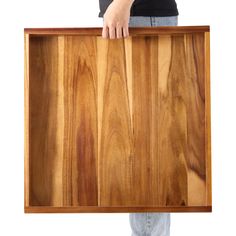 a person holding a large wooden tray with wood grains on it's sides