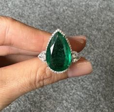 A one-of-a-kind, classic 9.37 carat Zambian Emerald center stone, with 0.62 carat of pear-shaped Diamonds and 0.22 carat of round cut Diamonds around it, all set in 18K solid White Gold. The Emerald is transparent, lustrous and of an ideal vivid green color, making it a very eye-catching engagement or cocktail ring. 18K White Gold: 6.34 Grams  Emerald pear shaped: 9.37 Ctw (1200 )  Diamond Pear Shape: 0.62 Ctw Diamond Round: 0.22 Ctw Luxury Pear-shaped Diamond Ring With 17 Jewels, Luxury Pear-shaped Brilliant Cut Emerald Ring, Luxury Pear-shaped Emerald Ring For Formal Occasions, Luxury Pear-shaped Emerald Ring With Prong Setting, Gia Certified Pear-shaped Diamond Emerald Ring, Formal Pear-shaped Emerald Ring In White Gold, Formal Pear-shaped Emerald Ring With Diamond, Gia Certified Teardrop Diamond Ring For Formal Occasions, Elegant Gia Certified Teardrop Diamond Ring