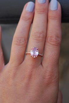 a woman's hand with a ring on it and a pink stone in the middle