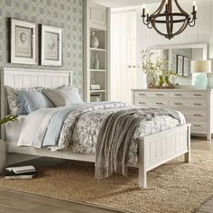 a white bed sitting in a bedroom on top of a wooden floor next to a dresser