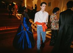 a man in a white shirt and blue jeans is standing next to two other people