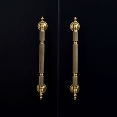 two golden door handles on a black wall