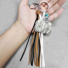 a person's hand holding a tasseled keychain