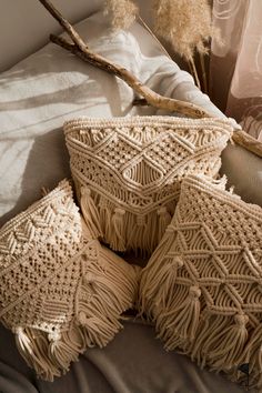 four decorative pillows sitting on top of a bed next to dry grass and dried plants