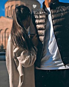 a man and woman standing next to each other in front of a building with a sky background