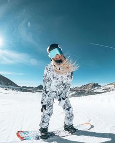 a snowboarder is standing in the snow with her board and goggles on