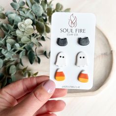 someone is holding up some cute little ghost earring studs that are white and orange