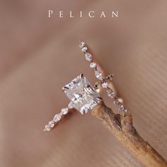 an engagement ring with a princess cut diamond on the side, sitting on top of a twig