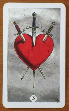 a tarot card with two swords on top of a heart and the number 3