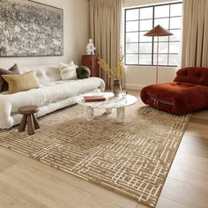 a living room filled with furniture and a large painting on the wall above it's windows