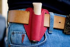 a person wearing a red leather belt with a knife in their back pocket