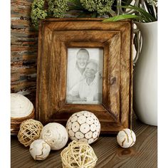 a wooden frame with some white balls in front of it on a table next to a potted plant