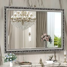 a large mirror with a chandelier hanging from it's side next to a table