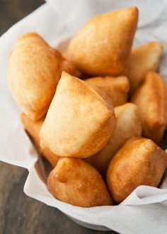 a basket filled with cut up doughnuts on top of a wooden table next to a white napkin