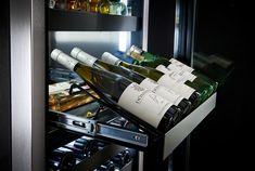 several bottles of wine are sitting in an open refrigerator