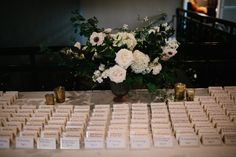 flowers and place cards on a table at a wedding reception, with candles in the background