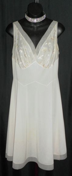 "Made by Vanity Fair, color is an off white, antique white, light beige, whichever you would like to call it, so pretty. This halter style gown is ultra flattering with satin stitched embroidery on the bust and chiffon trim on the bodice and hemline. I do see some light colored stains on the lower half of the gown, you may be able to see them in the photo of the hemline. I did launder but they didn't seem to come out. Relatively light so they aren't as obvious. Bust 38\" Waist 32\" Hips up to 46 Vintage Beige Dress For Wedding Night, Elegant Cream Wedding Nightgown, Feminine White Nightgown For Evening, Feminine White Evening Nightgown, Fitted Cream Nightgown For Wedding, Vintage Cream Sheer Nightgown, Vintage White Nightgown For Wedding Night, Cream Sleeveless Vintage Dress For Wedding, Sleeveless Cream Nightgown For Wedding