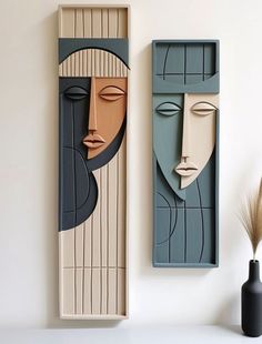 two wooden faces are on display next to each other in front of a white wall