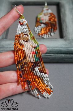 the beaded earrings are being held up by someone's hand