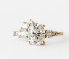 three stone engagement ring in yellow gold with diamonds on the sides and an oval cut diamond center