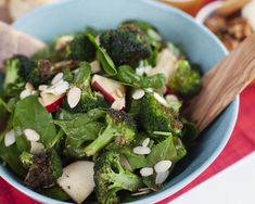 a blue bowl filled with broccoli and radishes on top of a table