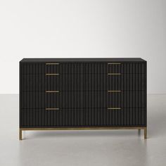 a black dresser with gold handles and drawers on the bottom, against a white wall