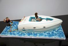 there is a cake shaped like a boat and two people on the water in it