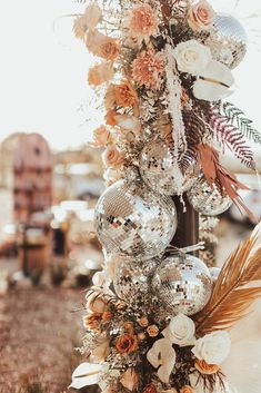 a bunch of ornaments are hanging from a pole with flowers and feathers on it, along with other decorations