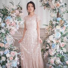 a woman standing in front of a floral arch