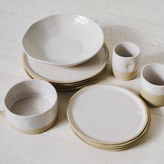 a table topped with white plates and cups next to each other on top of a wooden floor