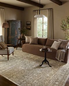 a living room filled with furniture and a rug on the floor next to a window