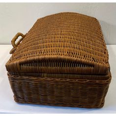 a brown wicker box with handles on a white surface